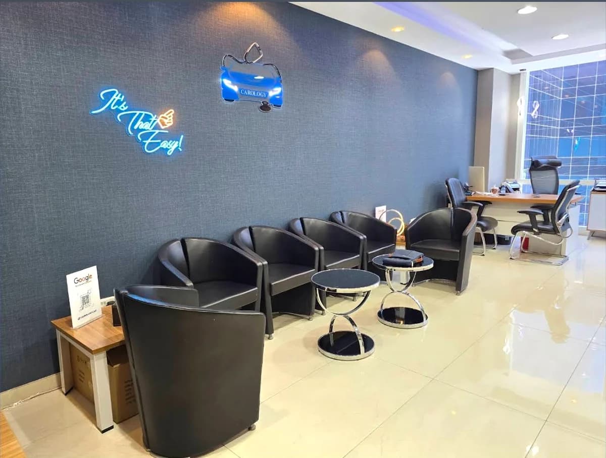 Inside the Carology office in Business Bay, Dubai, with the Carology logo and It's That Easy neon sign on the wall